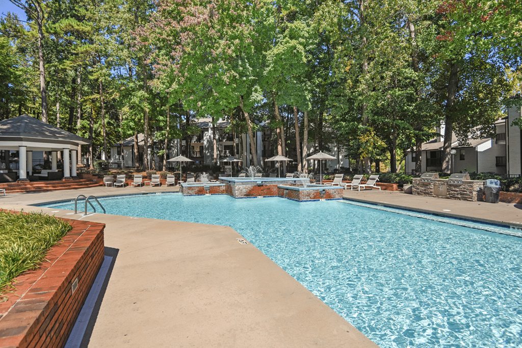 A pool surrounded by trees and a gazebo at Paces Pointe Apartment Homes, Matthews, NC, 28105