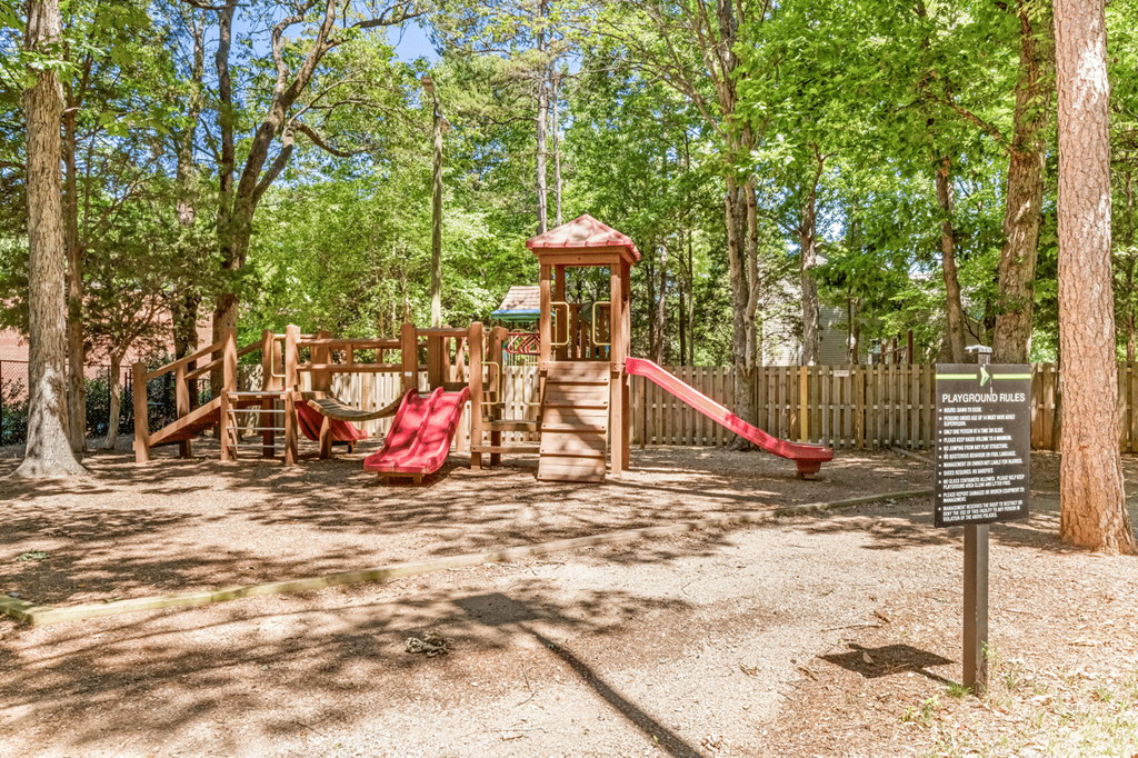 A playground with a red slide and a wooden structure at Paces Pointe Apartment Homes, North Carolina