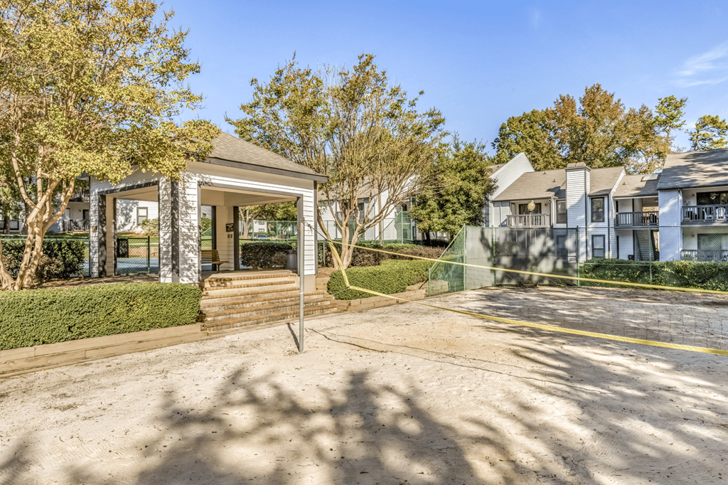 A building with a glass door and windows is surrounded by trees and a clear sky at Paces Pointe Apartment Homes, Matthews, 28105