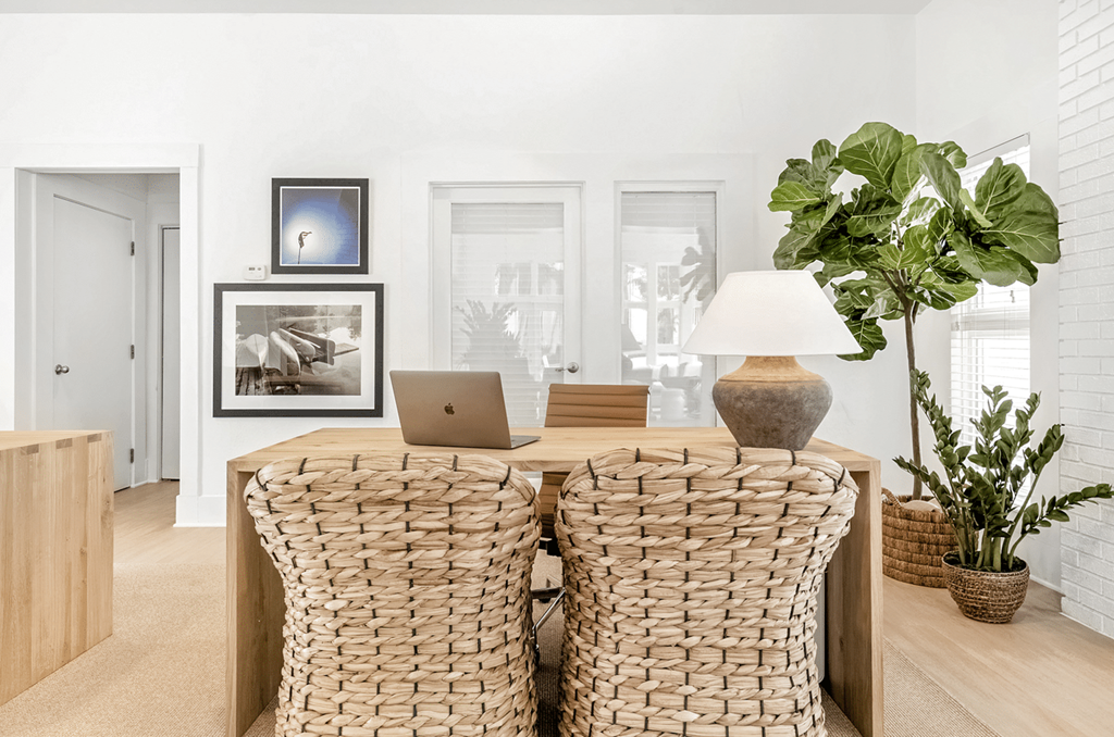 Two wicker chairs are in front of a white wall with a framed picture and a laptop on the table at Paces Pointe Apartment Homes, North Carolina