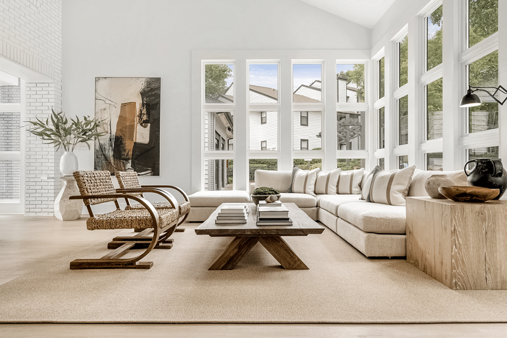 A living room with a white couch, a wooden coffee table, and a large window with a view of the outside at Paces Pointe Apartment Homes, North Carolina