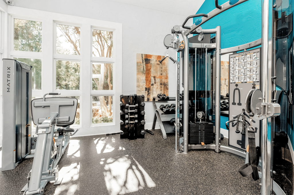 A gym with a variety of equipment including a treadmill, weights, and a bench press at Paces Pointe Apartment Homes, Matthews, North Carolina