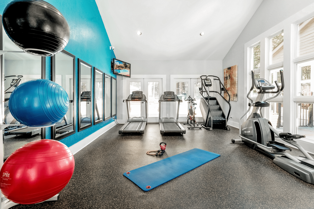 A gym with a blue wall and a variety of exercise equipment at Paces Pointe Apartment Homes, Matthews, North Carolina