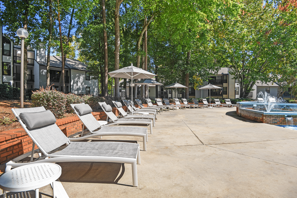 A pool area with chairs and umbrellas at Paces Pointe Apartment Homes, North Carolina