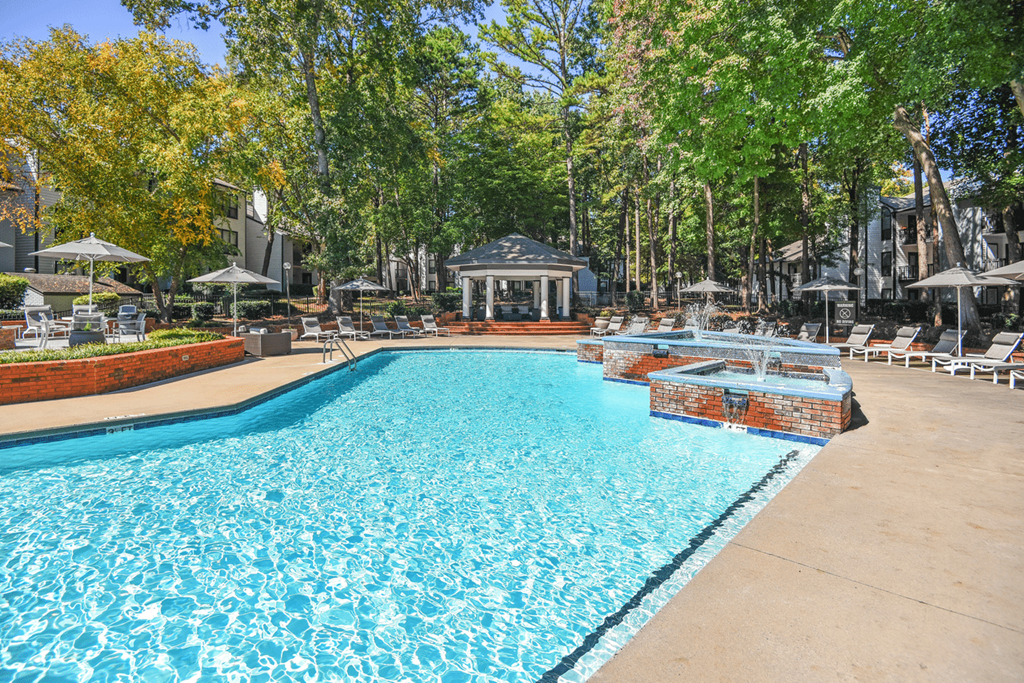 A large swimming pool surrounded by trees and a gazebo at Paces Pointe Apartment Homes, Matthews, NC