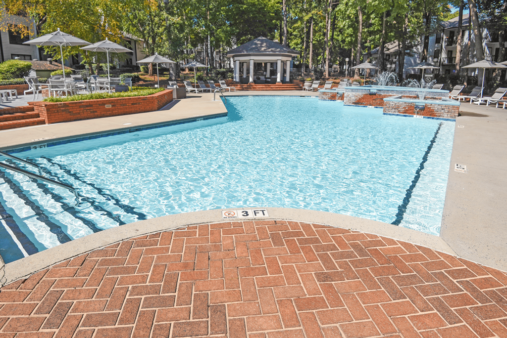 A swimming pool with a brick border and a fountain in the background at Paces Pointe Apartment Homes, North Carolina, 28105