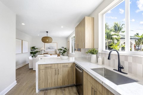 A modern kitchen with wooden cabinets and a large window.