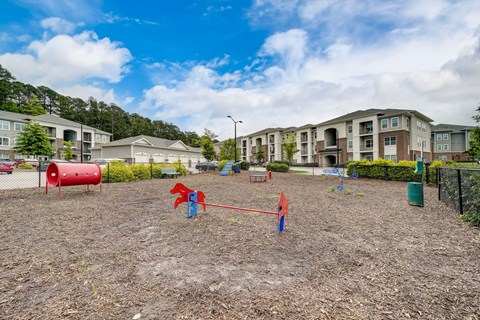 A playground with a swing set and a red barrel.