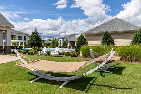 A lawn with a hammock and a house in the background.