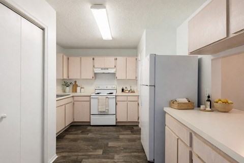 A kitchen with a white refrigerator and wooden floors.