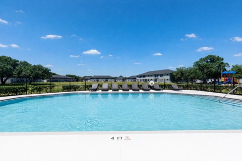 A swimming pool with a blue sky and clouds in the background.