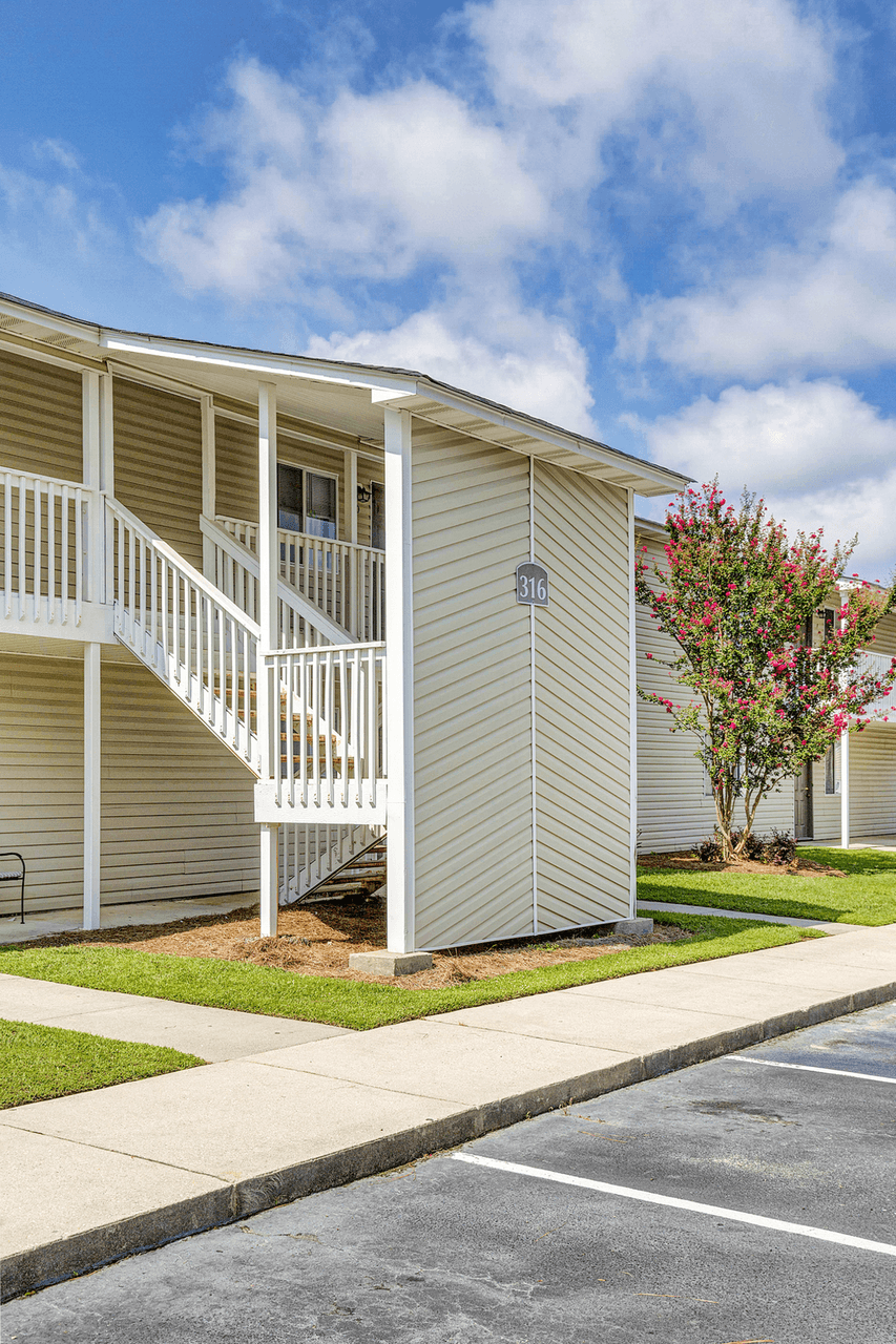 a building with stairs and a tree in front of it at Patriot Point Apartment Homes, Spring Lake, 28390 