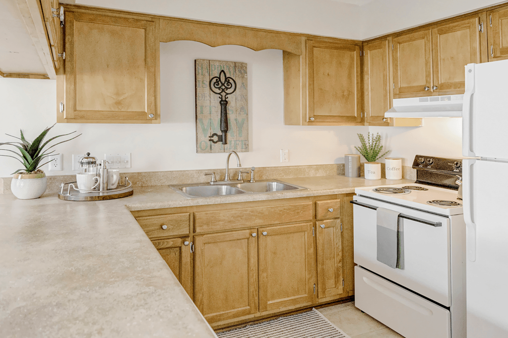 a kitchen with white appliances and wooden cabinets at Patriot Point Apartment Homes, North Carolina 