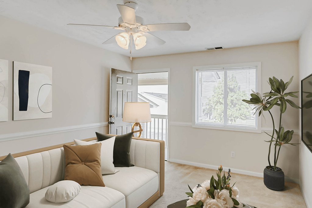 a living room with a white couch and a ceiling fan at Patriot Point Apartment Homes, Spring Lake, NC 