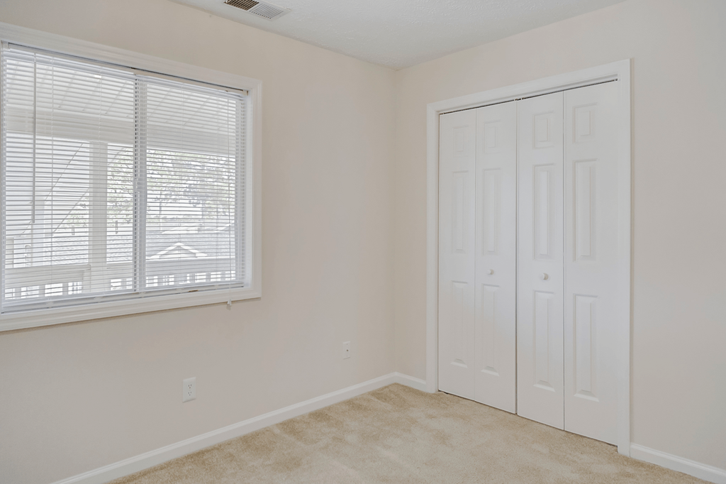 an empty bedroom with a large window and a white closet at Patriot Point Apartment Homes, Spring Lake, NC 28390