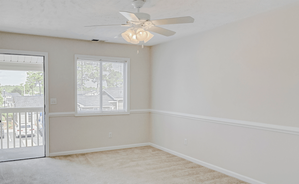 an empty bedroom with a ceiling fan and a door to a balcony at Patriot Point Apartment Homes, Spring Lake North Carolina 
