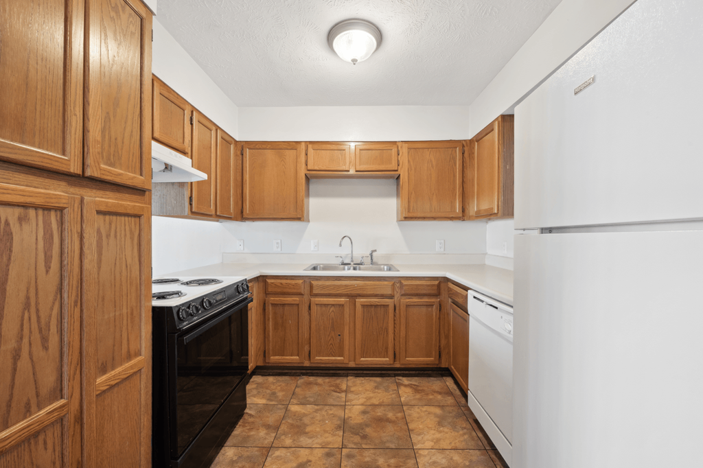 an empty kitchen with wooden cabinets and white appliances at Patriot Point Apartment Homes, Spring Lake 