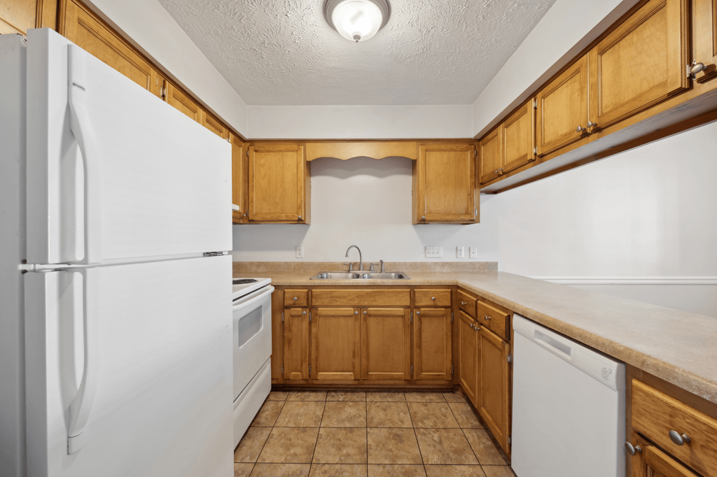 a kitchen with white appliances and wooden cabinets at Patriot Point Apartment Homes, Spring Lake North Carolina 