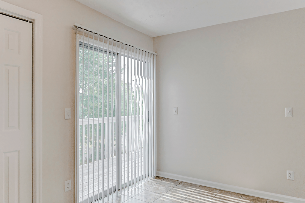 an empty room with a sliding glass door and a window at Patriot Point Apartment Homes, North Carolina, 28390