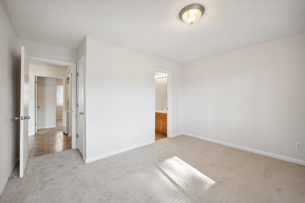 an empty living room with white walls and a white door to a hallway at Patriot Point Apartment Homes, Spring Lake, NC 