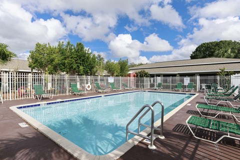 A large outdoor swimming pool surrounded by green chairs.