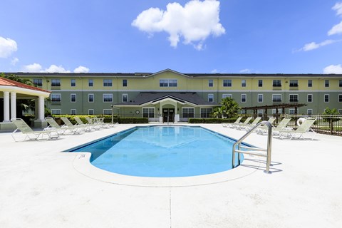 A large swimming pool in front of a hotel.