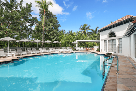 A large swimming pool surrounded by trees and lounge chairs.