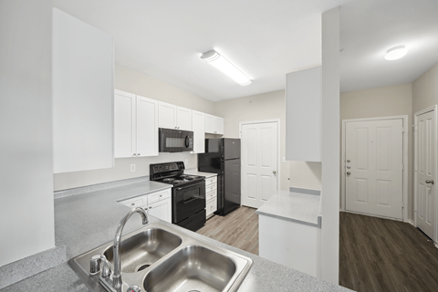 A kitchen with white cabinets and a black stove top oven.