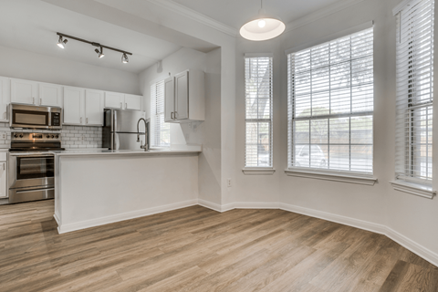 a kitchen with white cabinets and a large window