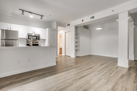 a spacious living room with a kitchen in the background