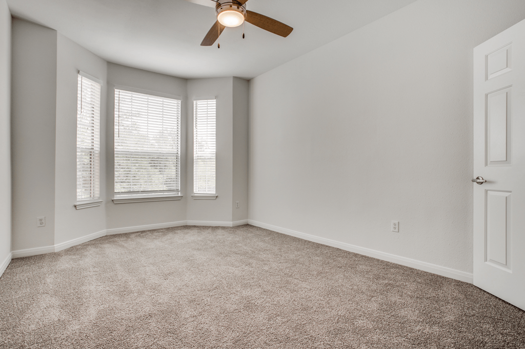 a bedroom with a ceiling fan and three windows