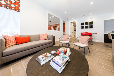 a living room with white walls and a brown coffee table with a pile of books on it