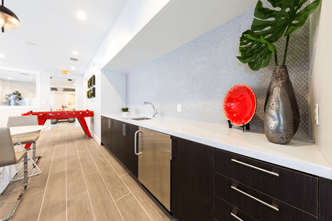 a kitchen with dark cabinets and a red table in the background