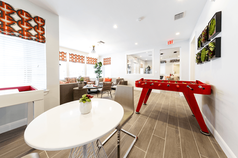 a room with a pool table and a table with a vase of flowers on it