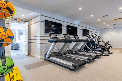 a gym with treadmills and televisions