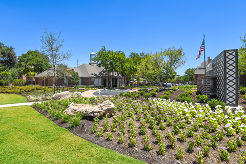a garden with a flag and a building in the background
