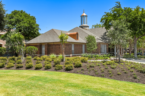 a large lawn with a flower garden in front of a building