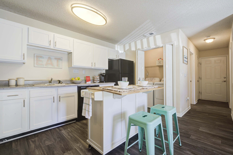 A kitchen with white cabinets and a black fridge.