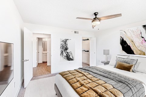 A bedroom with a large bed and a ceiling fan.