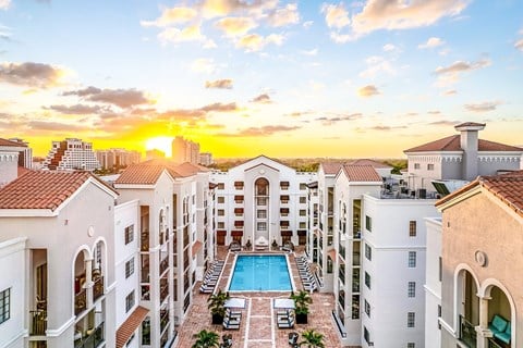 A sunset view of a pool surrounded by apartment buildings.