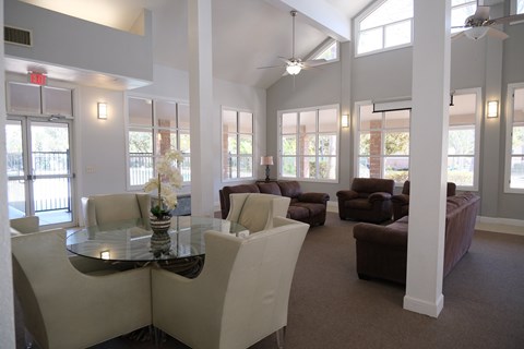A living room with a glass table surrounded by chairs and a fan.