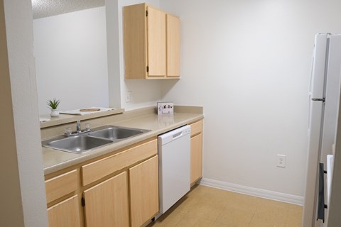 A kitchen with a white dishwasher and wooden cabinets.