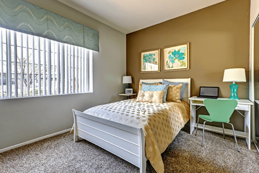 a bedroom with a bed and a desk with a laptop