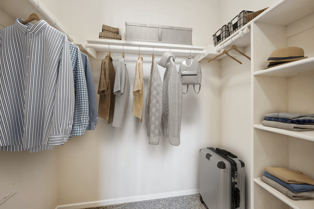 a walk in closet with white walls and shelves and a white rod with clothes hanging on it