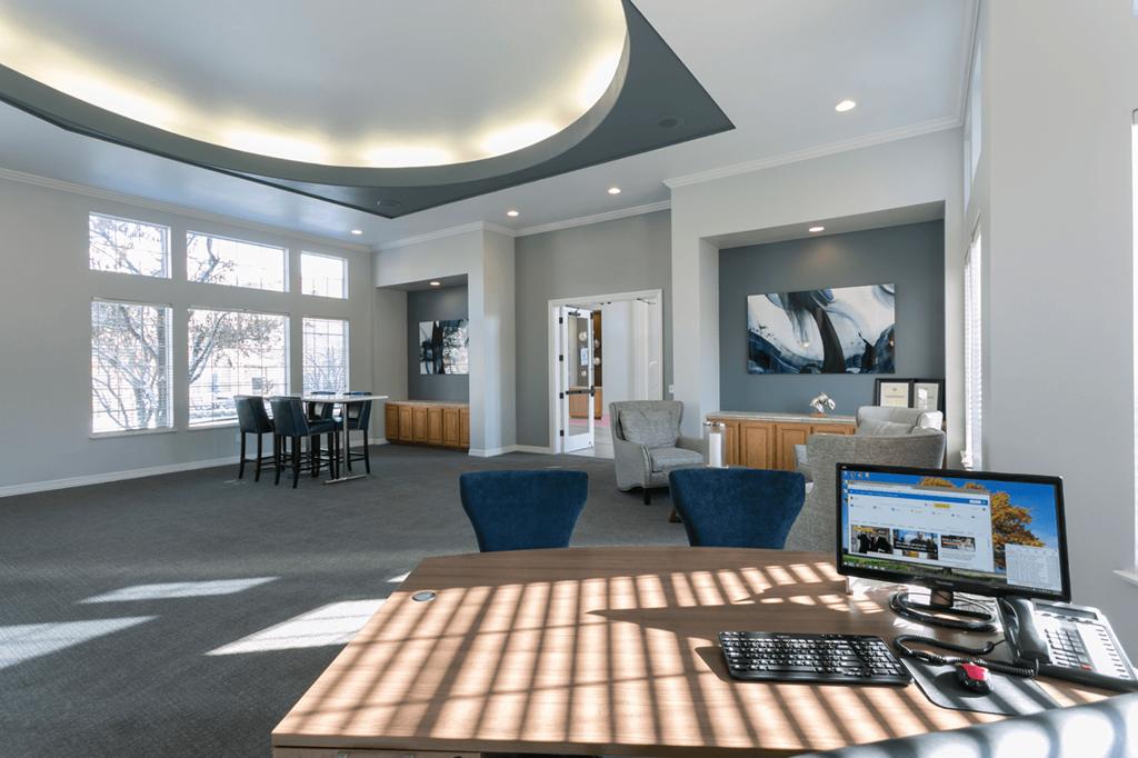 a computer sits on a desk in a large room with a dining table and chairs
