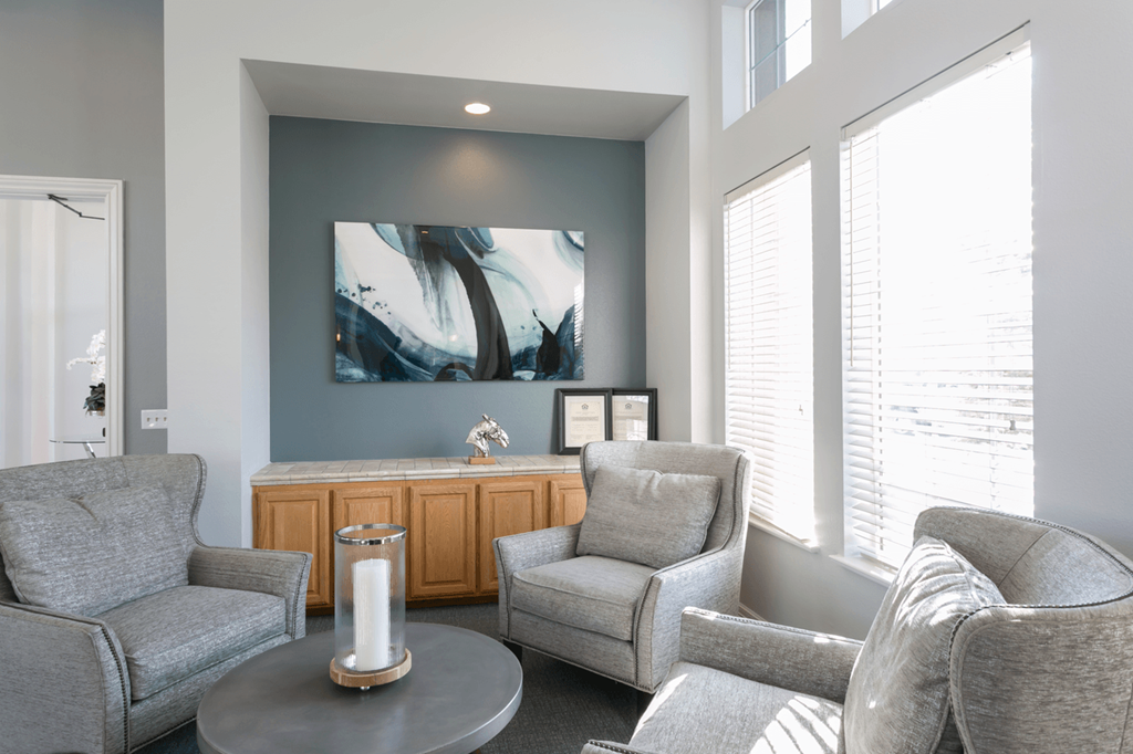 a seating area with chairs and a coffee table in front of a wall with a large painting