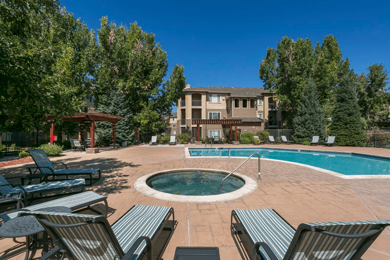 a swimming pool with lounge chairs and trees in the background