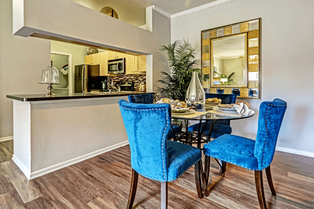 a dining area with a table and chairs and a kitchen in the background