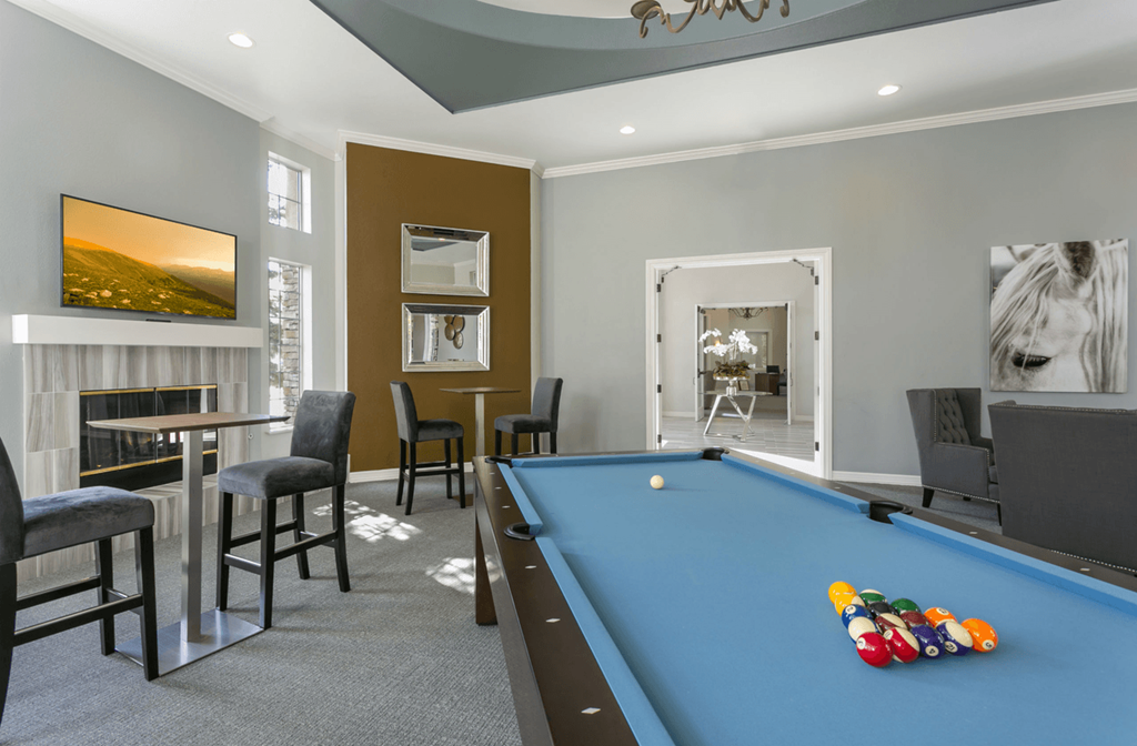 a games room with a pool table and chairs