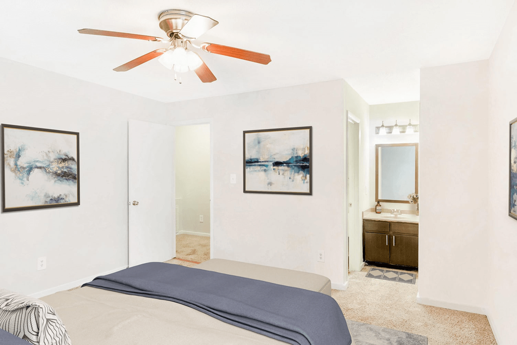 A bedroom with a bed, a ceiling fan, and two framed pictures on the wall at Regency Park Apartment Homes, Raleigh, 27616